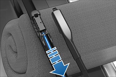 Paño doblado debajo de la escobilla con una flecha apuntando hacia fuera para indicar cómo se debe quitar la manguera del lavaparabrisas